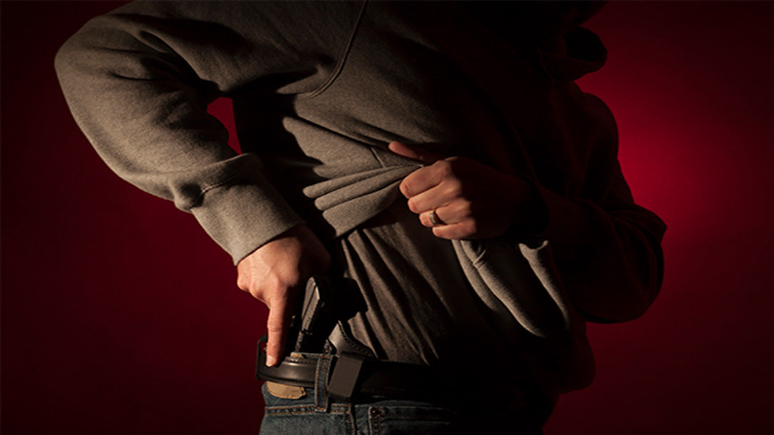 An individual drawing a pistol from the holster.